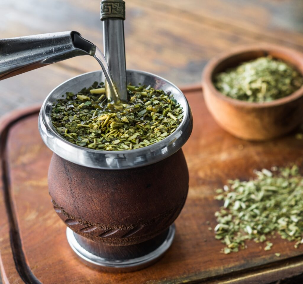 Water poured over yerba mate leaves in a traditional vessel